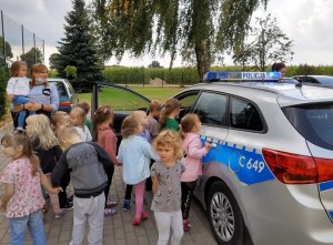 Policjantka wśród dzieci oglądających radiowóz